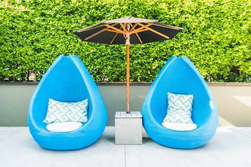 Deux fauteuils bleus avec un parasol noir sur une terrasse